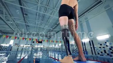 一位残疾游泳运动员在泳池旁热身，后景。